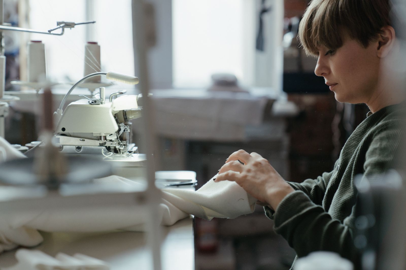 A garment is guided through a sewing machine in an alterations workroom.